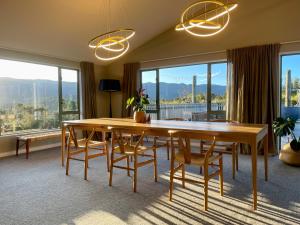 a dining room with a table and chairs and windows at Kaiteriteri Ridge Holiday Estate in Kaiteriteri