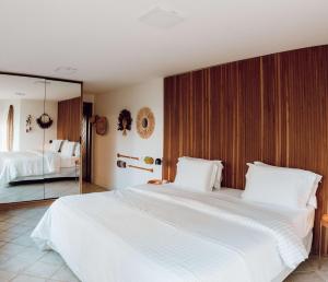 1 dormitorio con 2 camas blancas grandes y espejo en Naatooh Guest Houses, en Florianópolis