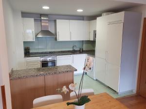 uma cozinha com armários brancos e uma mesa de madeira em Luminoso piso con terraza y aparcamiento ESS01636 em Hondarribia