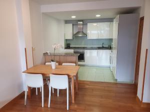 a kitchen with a wooden table and white cabinets at Luminoso piso con terraza y aparcamiento ESS01636 in Hondarribia