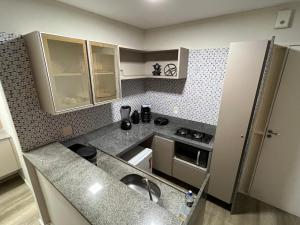 een kleine keuken met een spoelbak en een aanrechtblad bij Flat Boa Viagem luxo in Recife