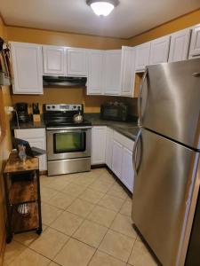 a kitchen with a stainless steel refrigerator and white cabinets at Camping Funhouse #3 in Tobyhanna