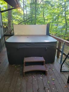 a hot tub sitting on a deck with a bench at Camping Funhouse #3 in Tobyhanna