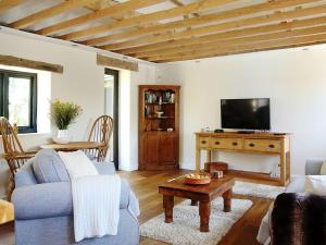 a living room with a blue couch and a tv at Ivy Cottage in Westfield