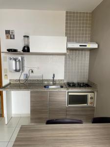 a kitchen with a sink and a microwave at Apartamento Riviera park in Caldas Novas