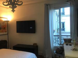 a bedroom with a bed and a television and a window at Cosy Flat 1 BDR Arc de Triomphe Champs Elysées in Paris