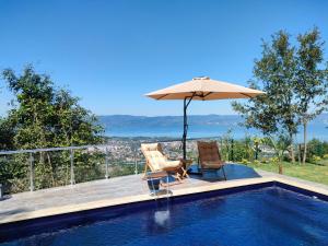 a swimming pool with two chairs and an umbrella at LakeviewhouseSapanca in Sapanca