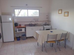 a kitchen with a table with chairs and a refrigerator at Ankara 5 in Las Grutas