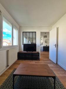 ein Wohnzimmer mit einem TV und einem Tisch in der Unterkunft T2 rénové avec parking gratuit sur place in Valence