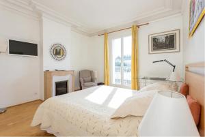een witte slaapkamer met een bed en een open haard bij J'aime Paris 1st in Boulogne-Billancourt