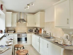 a kitchen with white cabinets and a sink and two stools at Sandhole Barn in Snodland