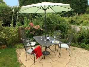 a table and chairs with a green umbrella at Sandhole Barn in Snodland