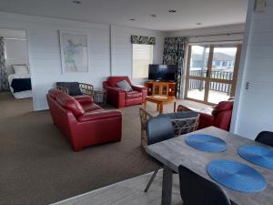 Whitianga Sea Views في وايتيانغا: غرفة معيشة بأثاث احمر وغرفة نوم