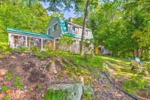 a house on a hill with a bench in front of it at Dreamy Bucksport Hideaway on Freshwater Pond! in Bucksport
