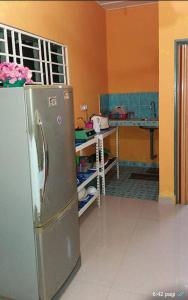 uma cozinha com um frigorífico de aço inoxidável num quarto em Dhia Irdina Homestay em Paya Rewak