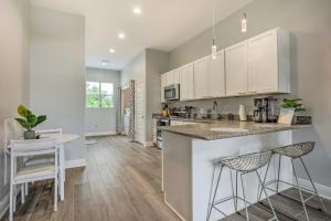 a kitchen with white cabinets and a large island with bar stools at Modern Long Beach Escape about 1 Mi to Shores! in Long Beach