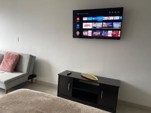 a living room with a tv on the wall and a chair at Hermoso Apartaestudio con excelente ubicación in Armenia