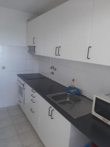 a white kitchen with a sink and a microwave at Lugar calmo na cidade sol 