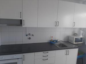 a kitchen with white cabinets and a sink and a microwave at Lugar calmo na cidade sol 