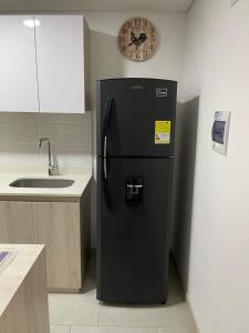 a black refrigerator in a kitchen with a clock on the wall at Hermoso Apartaestudio con excelente ubicación in Armenia