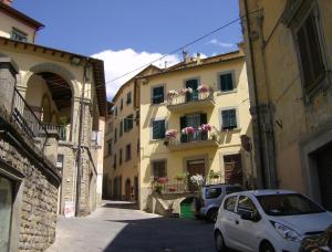 an alley with a building with flowers in a balcony at Le Finestre di San Michele in Castiglion Fiorentino