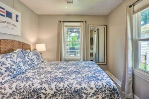 a bedroom with a blue and white bed and windows at Chic Cottage with Private Yard Steps to Beach! in Colonial Beach