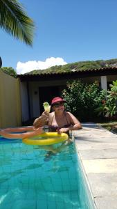 une femme dans un bassin avec une margarita dans l'établissement Pousada Yemanjá Cunhaú, à Barra do Cunhaú