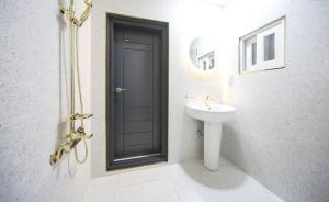 a bathroom with a sink and a black door at Masan First Class Hotel in Changwon