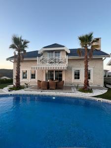 a large pool in front of a house with palm trees at Villa Ladybug Unique design of your dreams in Foca