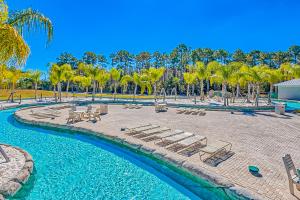 a resort pool with lounge chairs and palm trees at The Wharf 805 in Orange Beach