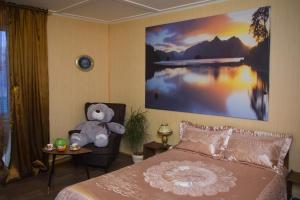 a teddy bear sitting on a chair in a bedroom at Roshchinskaya Guest house in Vostryakovo