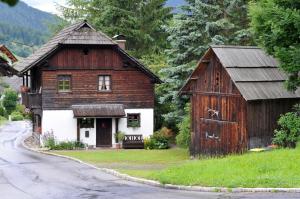 una casa vieja y un granero al lado de una carretera en Haus am Bach, en Bad Kleinkirchheim