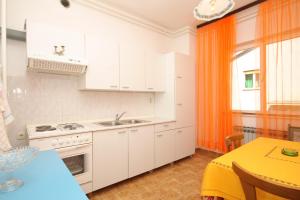 eine Küche mit weißen Schränken und einem orangen Vorhang in der Unterkunft Apartment Pula 7647a in Pula