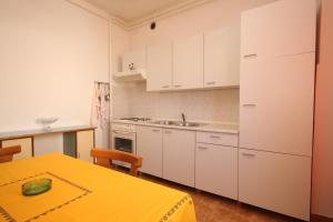 eine Küche mit weißen Schränken, einem Tisch und einem Waschbecken in der Unterkunft Apartment Pula 7647a in Pula