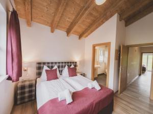 a bedroom with a large bed with red and white pillows at Chalet Anna XL Leogang in Leogang