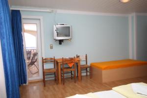 een kamer met een tafel en een tv aan de muur bij Triple Room Peroj 2235f in Peroj