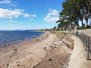 a sandy beach with a fence next to the water at Moorburn Heights in Largs