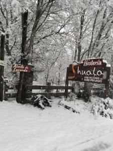 two signs in the snow next to a fence at Huala Hosteria in Lago Puelo