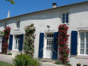 a white house with blue doors and flowers at Maison au cœur du Marais Poitevin avec barques, canoës, pédalo et vélos включены - FR-1-426-147 in Damvix
