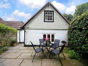 a patio with a table and chairs in front of a house at Sawmill Cottage in Royal Tunbridge Wells