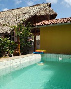 a swimming pool in front of a house with surfboards at Pousada Yemanjá Cunhaú in Barra do Cunhau