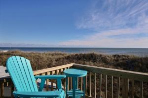 two blue chairs sitting on a deck overlooking the ocean at NC 12 56821-28 Condo in Hatteras +2 photos