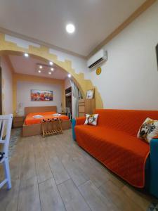 een woonkamer met een oranje bank en een bed bij Il Sole della Guilla in Palermo