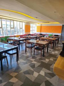 Cebu Dulcinea Hotel and Suites-MACTAN AIRPORT HOTEL في ماكتان: غرفة طعام مع طاولات وكراسي ونوافذ
