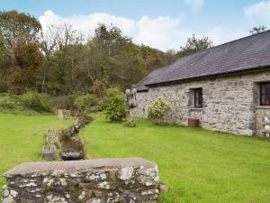 an old stone house with a stone wall in a yard at Ty Bach in Cilgwm