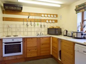 a kitchen with wooden cabinets and a stove top oven at Ty Bach in Cilgwm