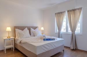 1 dormitorio con 1 cama con sábanas blancas y ventana en House Deja Blue, en Orebić