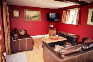 a living room with red walls and leather furniture at Crossroads Farm - Queen Anne's Stable in Box