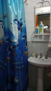 a bathroom with a sink and a dolphin shower curtain at Casargentina Apart Depto entero Baño privado 15min Ezeiza in Monte Grande