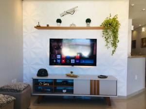 a living room with a tv on a wall at Casa moderna de praia em Itaipuaçu RJ in Maricá